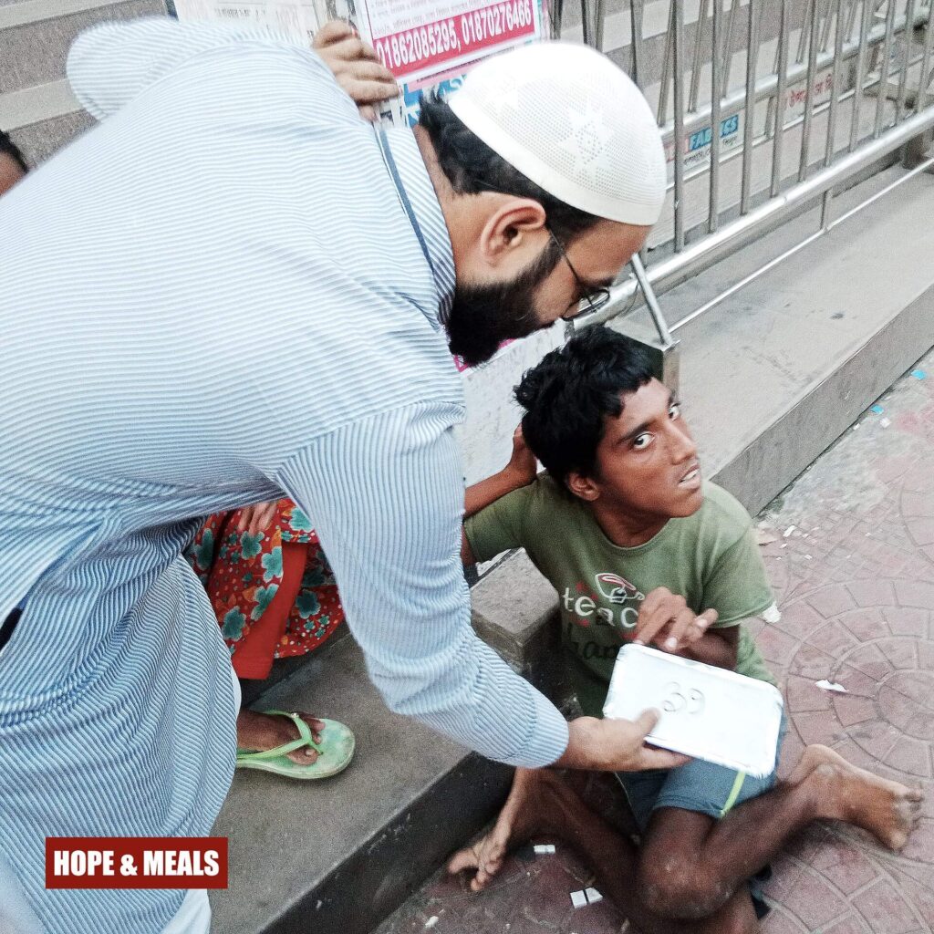 Hope & Meals volunteer handing a meal box to a physically disabled person with compassion.