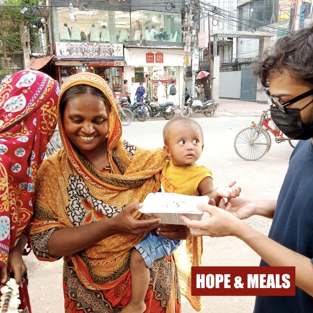 A smiling child receiving a free meal box from Hope & Meals volunteers.